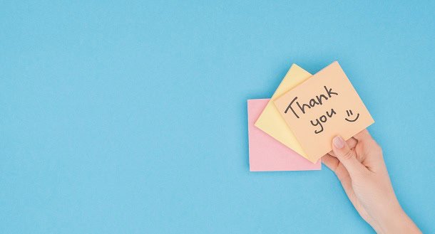 A hand holding a post-it note saying: Thank You!