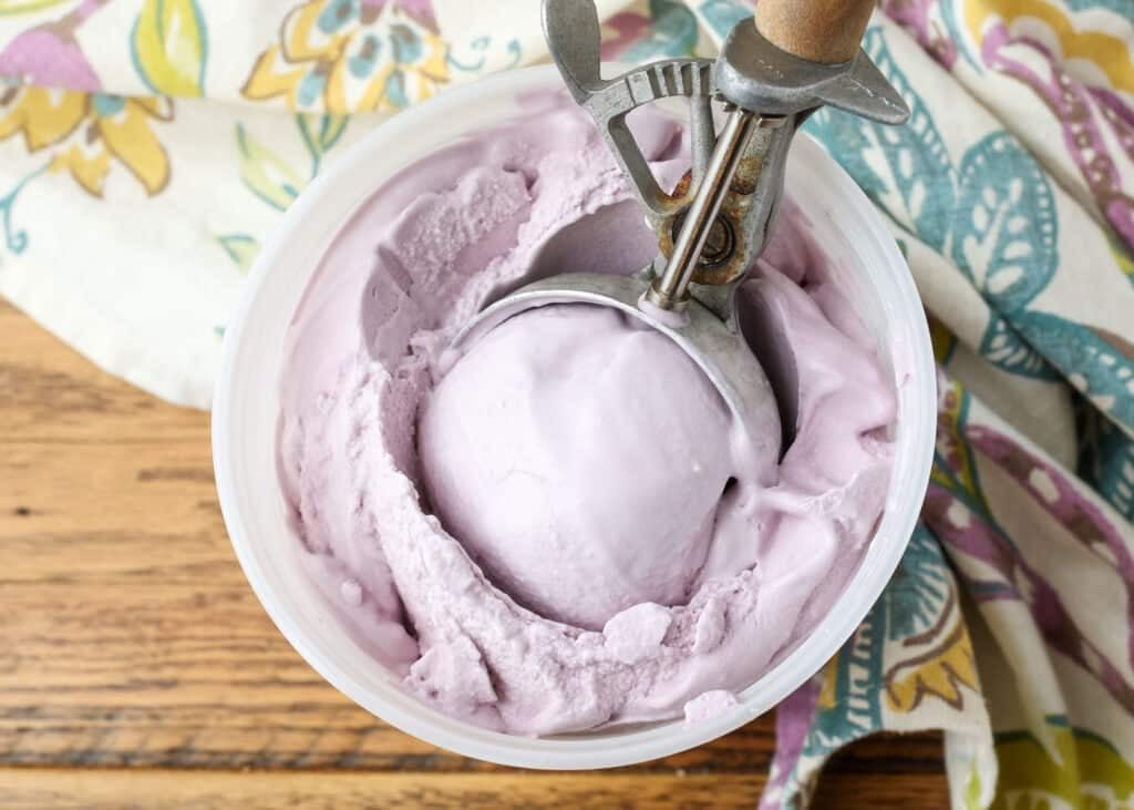 grape ice cream in bowl with wooden scoop