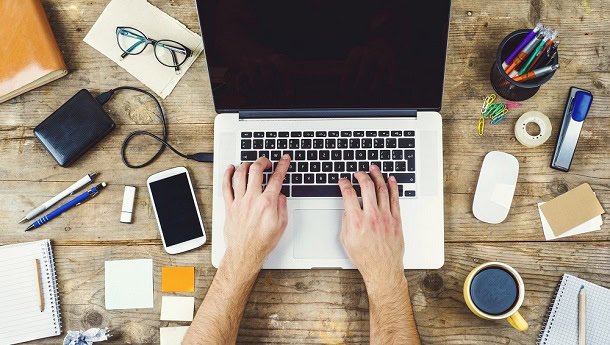 short_work_quotes.jpg A man working with a laptop with a coffee cup and other things on his desk.