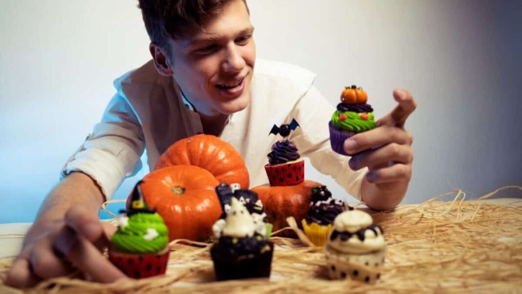 Teen holding Halloween decorated cupcakes and smiling
