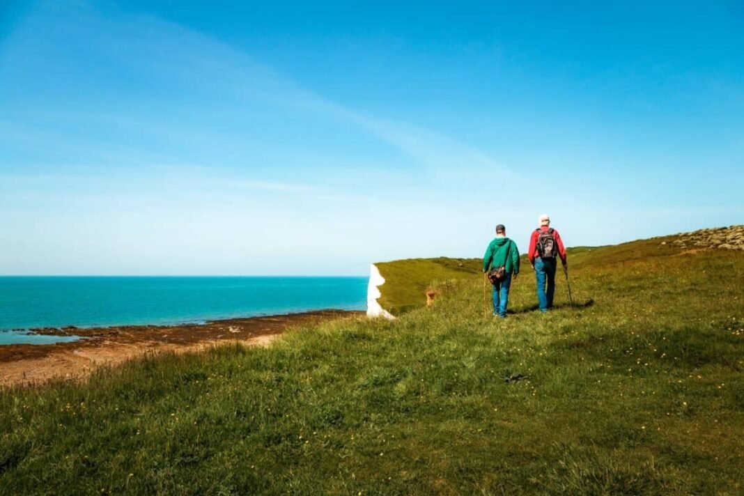 Why on earth did Diageo shares fall by 56%? Rear view image depicting two men hiking together with the stunning backdrop of Seven Sisters cliffs in the south of England.