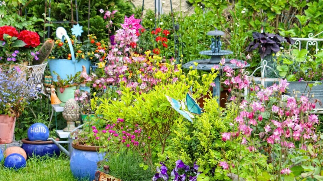 A wildlife garden in a small space showcases blooming perennials, native plants, shrubs, container plants, a birdbath, gardening decor, and artificial butterflies, creating a vibrant and inviting habitat.