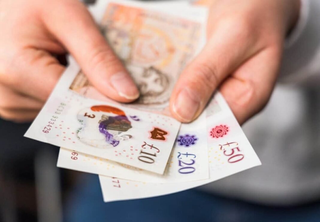 How large does my shares ISA need to be to Close-up of a woman holding modern polymer ten, twenty and fifty pound notes.