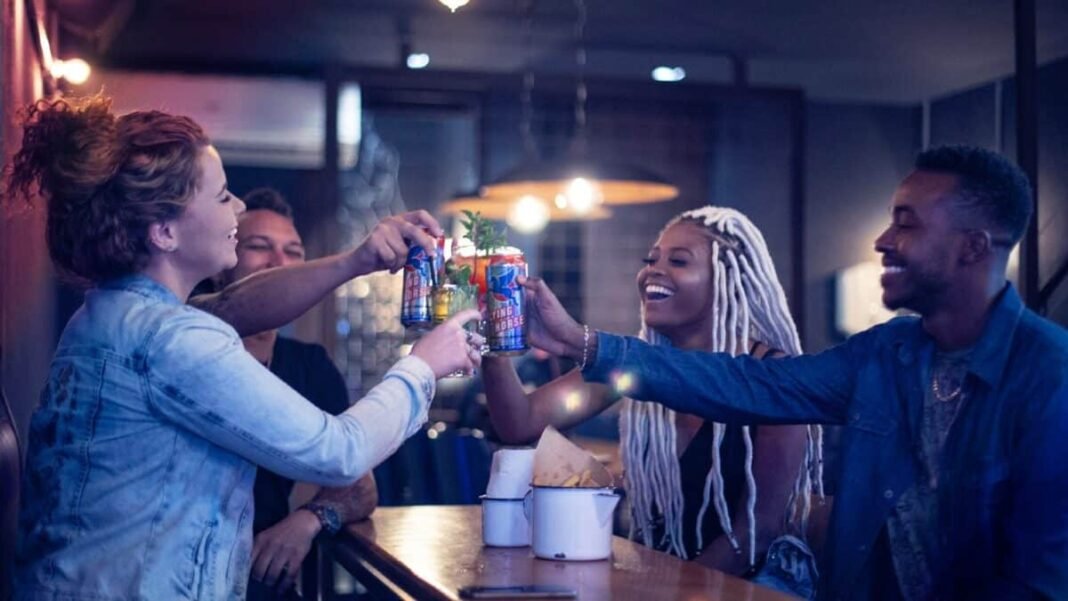 Group of four young adults toasting with Flying Horse cans in Brazil