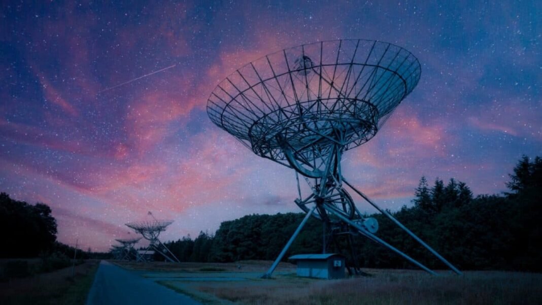 A row of satellite radars at night