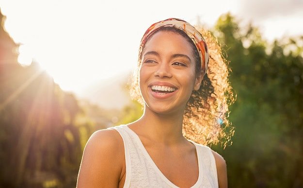 A smiling woman out in the sunshine.