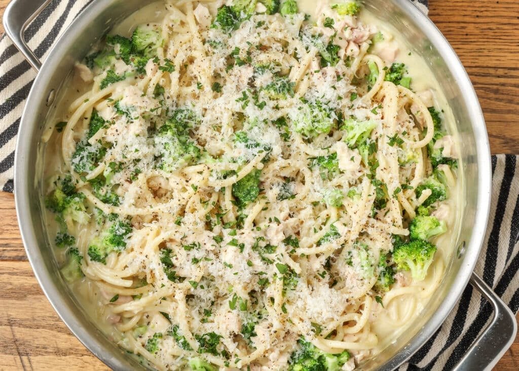 A close up horizontally aligned photo of a skillet full of chicken broccoli pasta.