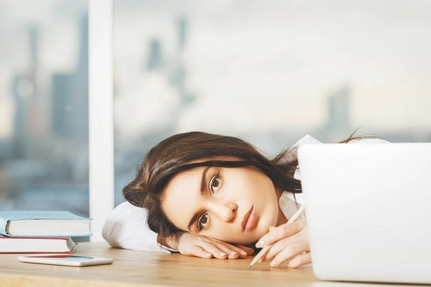 A woman in an office looking unmotivated and tired.