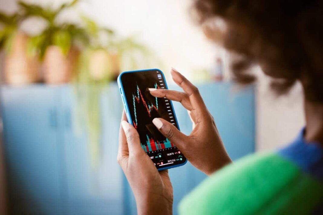 Centrica stock plummeted on the morning of the earnings announcement. Black woman using smartphone at home, watching stock charts.