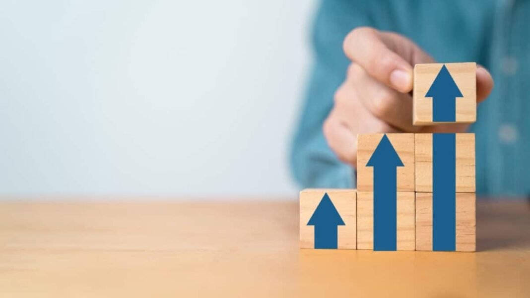 This little-known UK growth share has increased by 387% in Businessman hand stacking up arrow on wooden block cubes