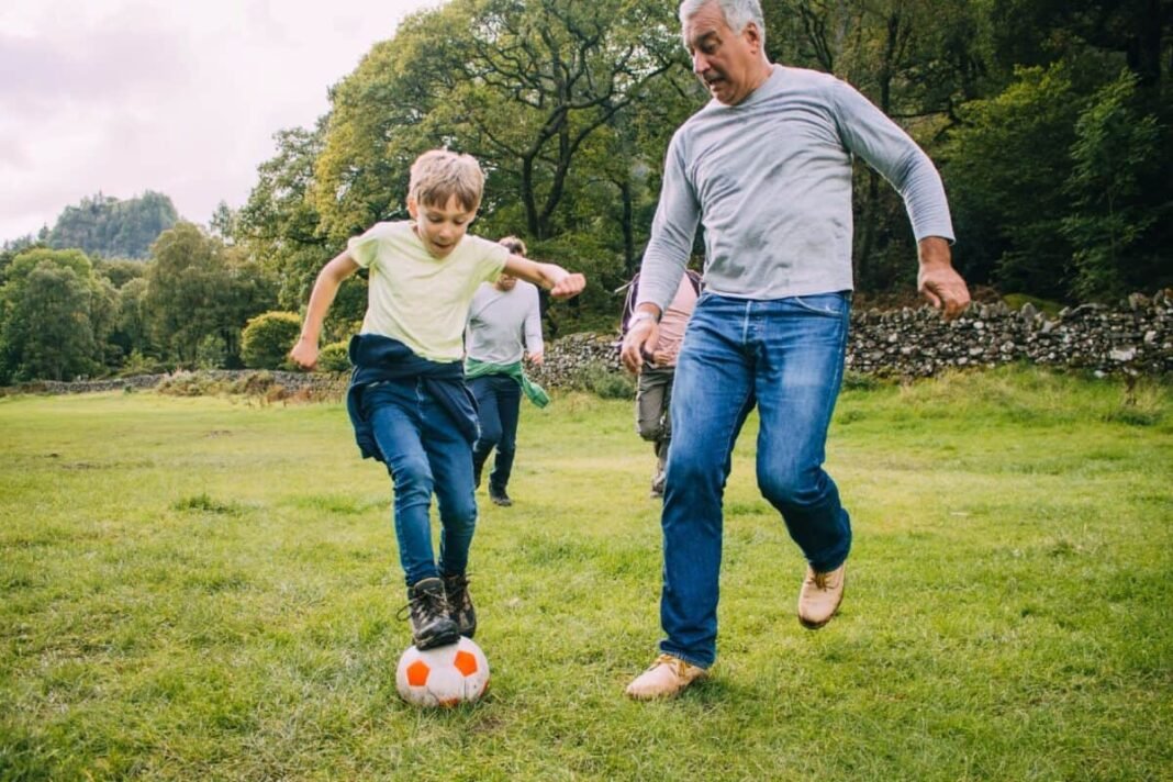 With a yield of 8.8% but down 15%, should you Three generation family are playing football together in a field. There are two boys, their father and their grandfather.