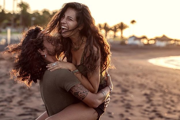 funny_inspirational_quotes.jpg A couple hugging and laughing on a beach.