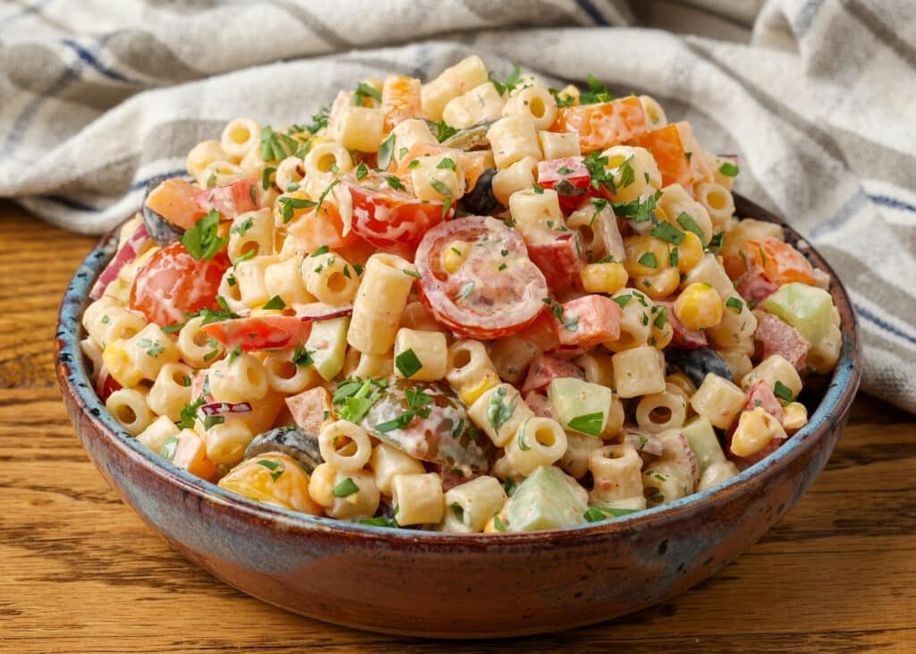 Southwest-Pasta-Salad-BFK-5-1024x731.jpg A horizontally aligned image showing a bowl of southwest pasta salad on a wooden tabletop.