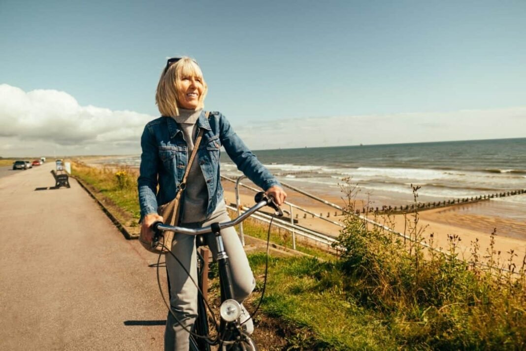 Woman riding her old fashioned bicycle along the Beach Esplanade at Aberdeen, Scotland.