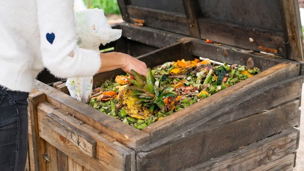 A close-up shot of a person beside a wooden pallet bin, showcasing how to start composting spring