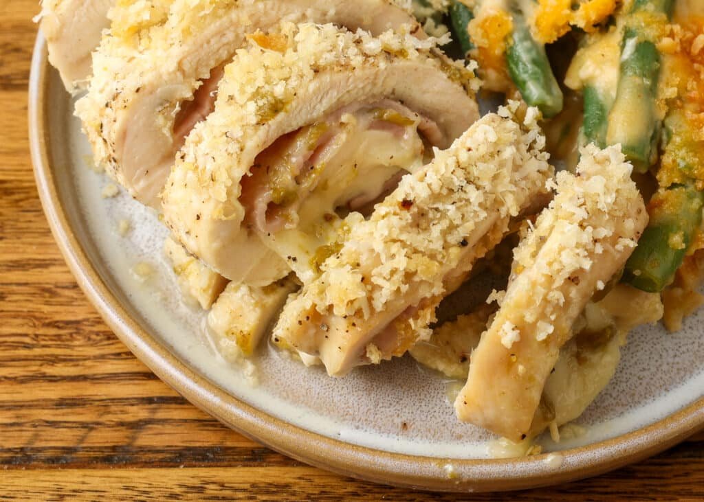 A close up view of the sliced Green Chile Chicken Cordon Bleu on a ceramic grey plate, showing the layers within. 