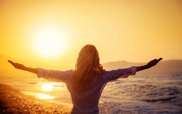 A woman on the beach at sunrise.