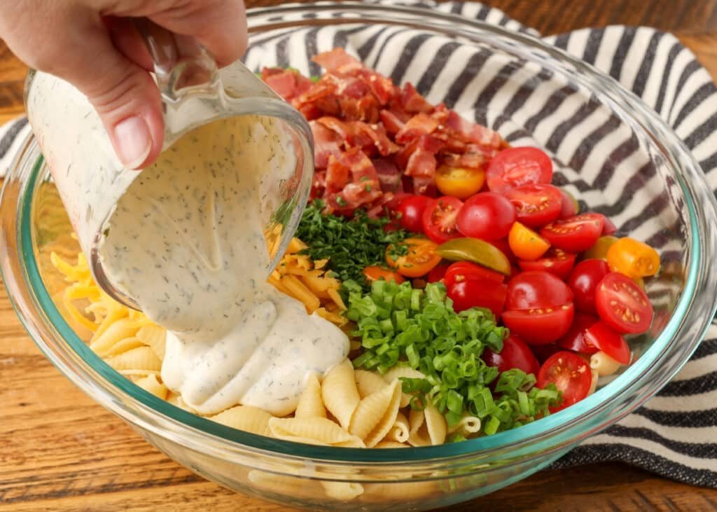 pour shot of ranch dressing over pasta salad